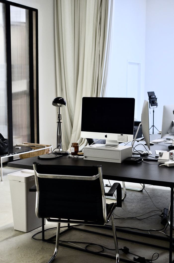 Modern workplace with convenient computer on black table and chair near wires on floor in office